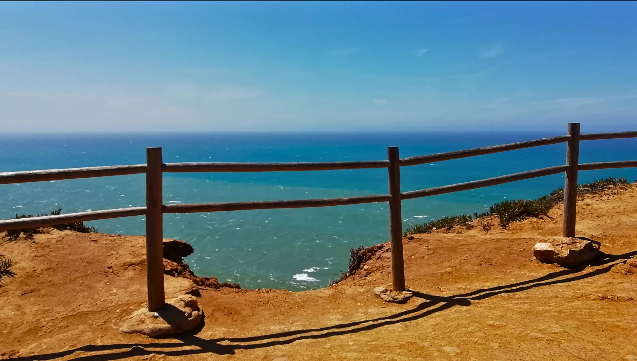 view on the ocean over the wooden fence from senior travel to Cabo da Roca,