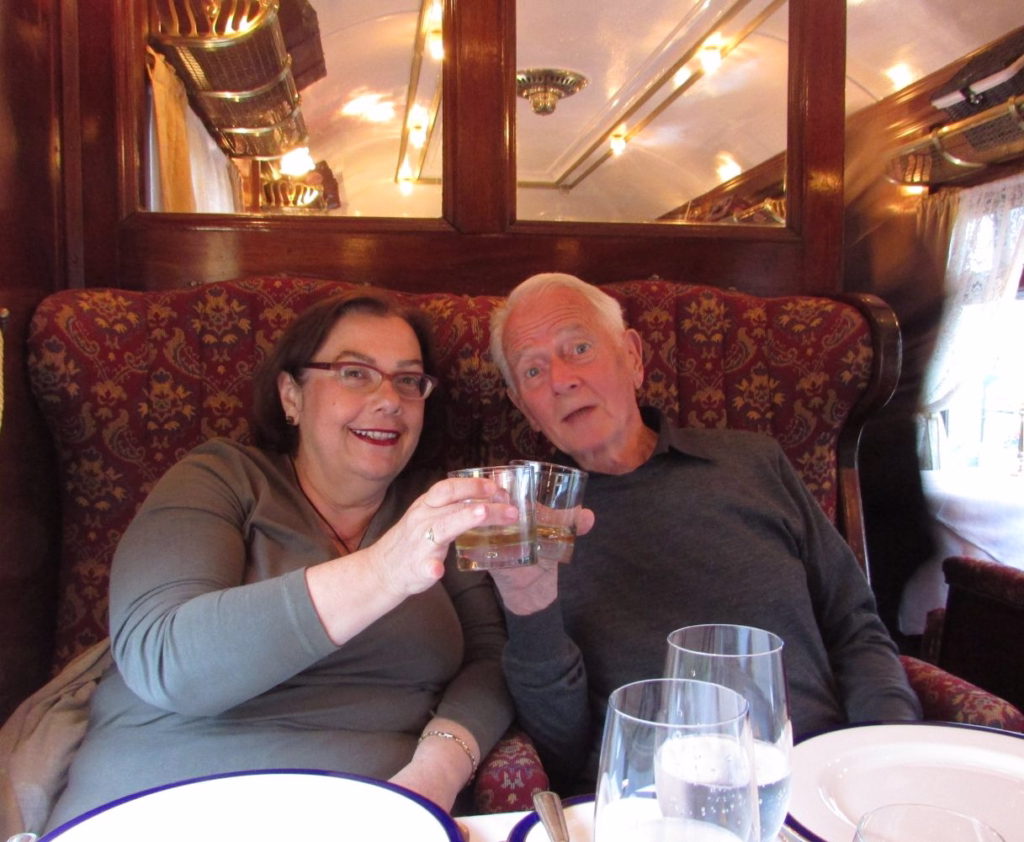 seniorglobetrotters in Orient Express Vagon restaurant holding glasses with whiskey